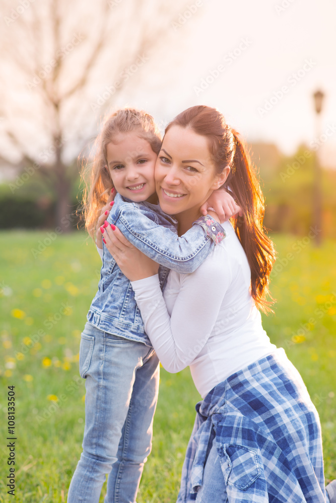 Beautiful young mother with her five years old daughter standing on the grass,and playing,colored photo Beautiful young mother with her five years old daughter standing on the grass,and playing,colored photo