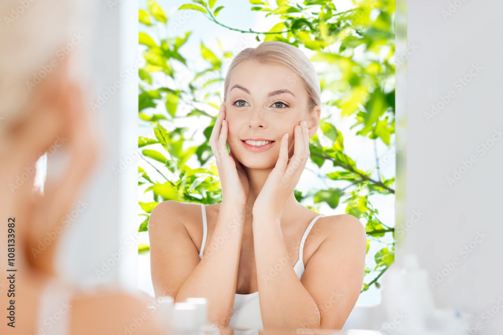 happy young woman looking to mirror at bathroom happy young woman looking to mirror at bathroom
