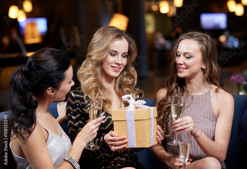 happy women with champagne and gift at night club