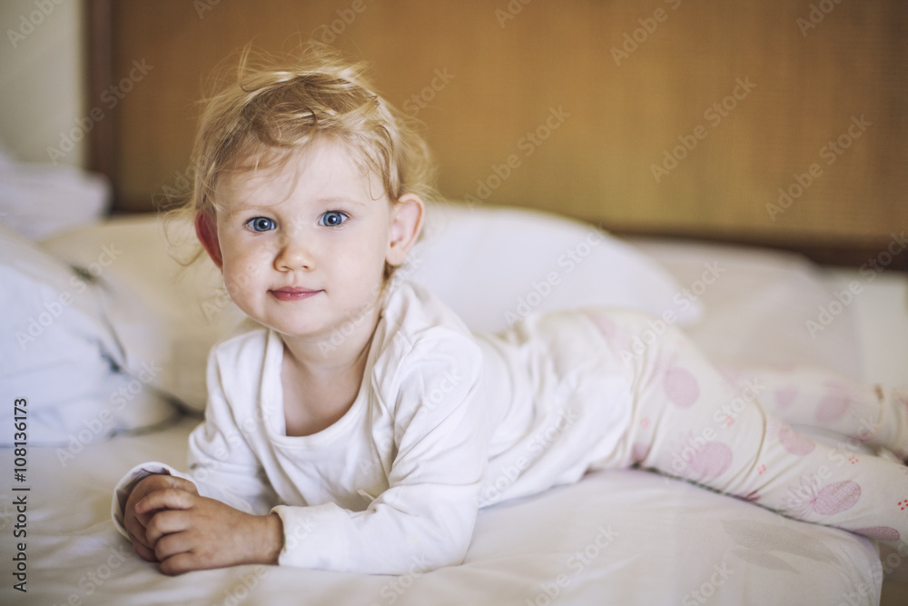 Small child lies in the bedroom on the bed and smiling Small child lies in the bedroom on the bed and smiling