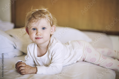 Small child lies in the bedroom on the bed and smiling