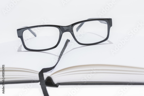 blank notice book with reading glasses