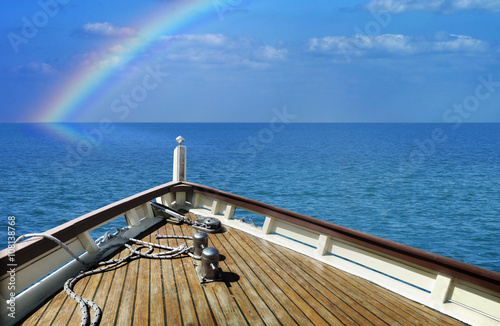 Ship in a calm sea. Rainbow on the horizon.