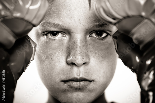 Child with boxing gloves focusing on punching pad