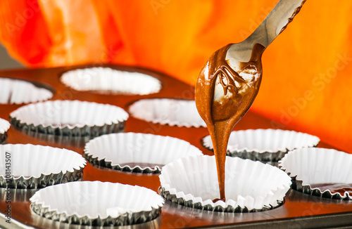 Pouring cake mix into baking muffins tray.