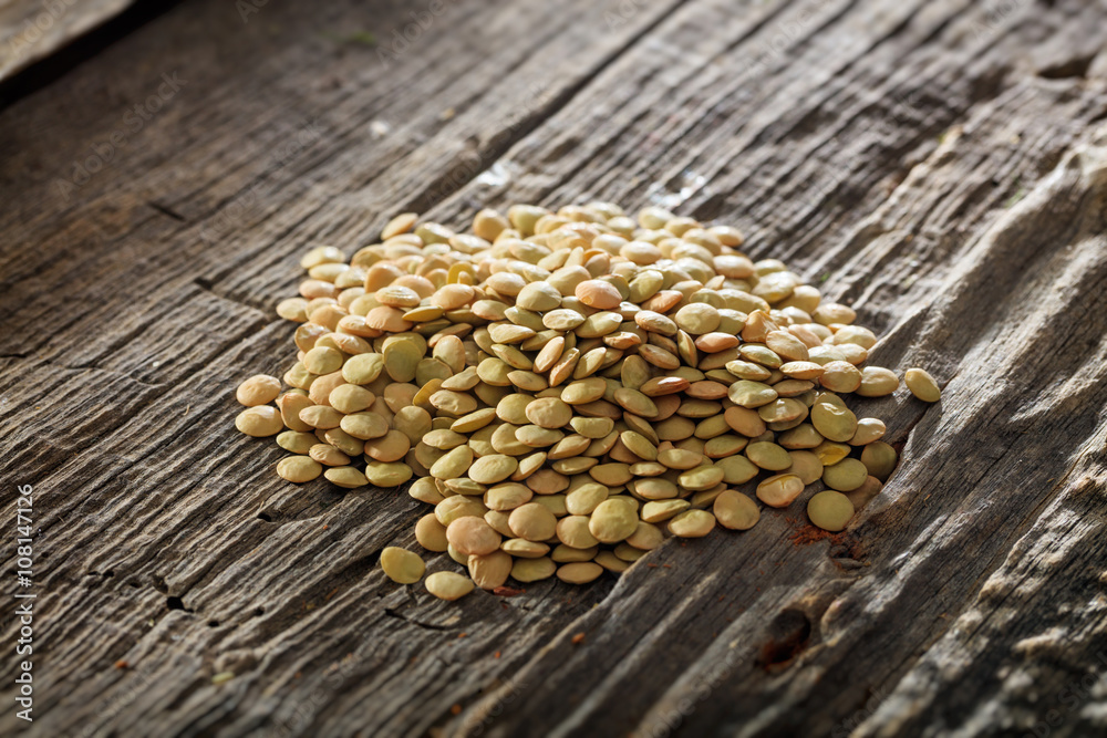 Obraz premium Brown lentils set on old wooden surface