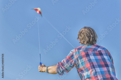 Man in grungy style flying a kite at the resort