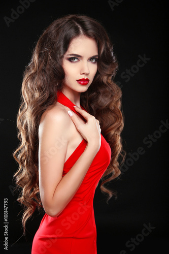 Beautiful girl with long wavy hair in red dress. Brunette with c