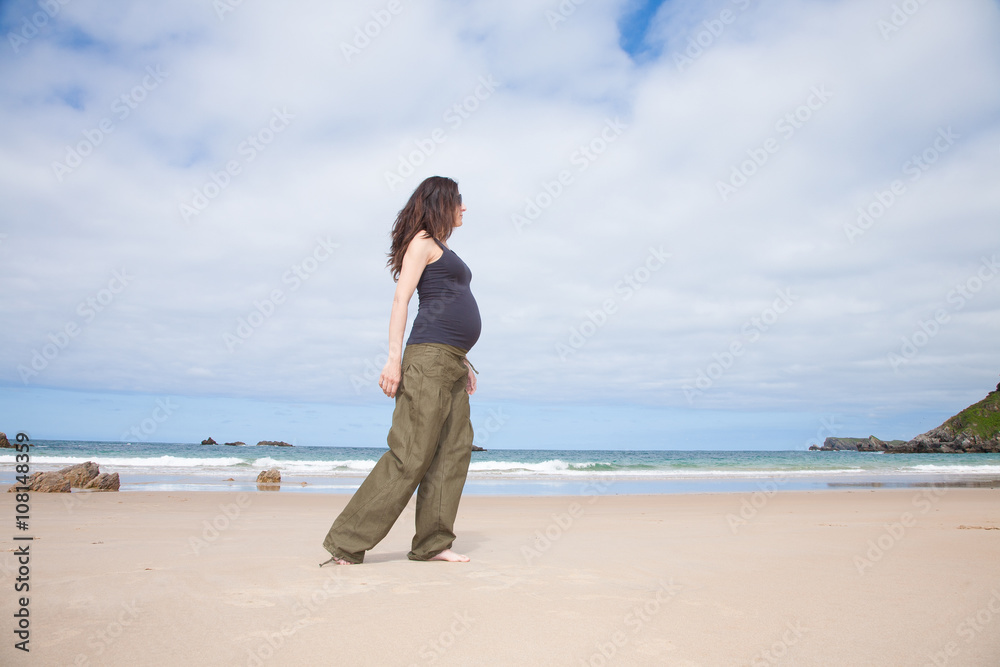 grey shirt pregnant walking next to ocean