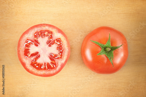 two fresh tomatoes on wooden cutting board