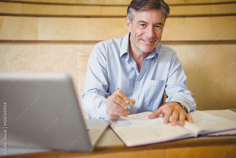 Portrait of happy professor writing in book at desk Portrait of happy professor writing in book at desk