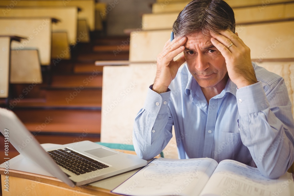 Fototapeta premium Depressed professor sitting with notes and laptop