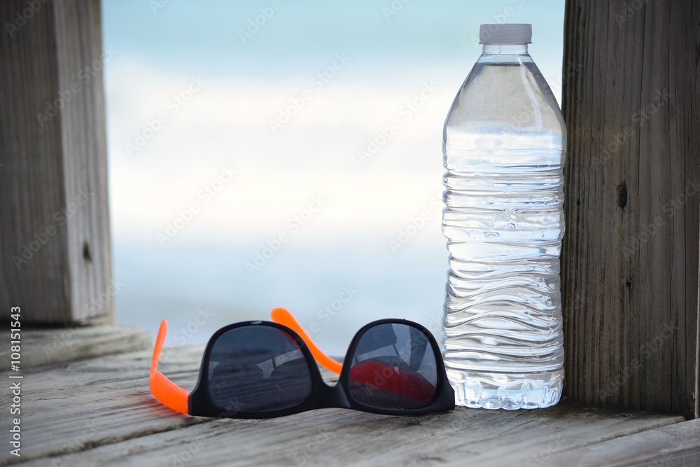 Pair of Shades and Bottled Water on Beach Boardwalk