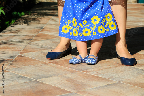 mother helping little daughter to make first steps