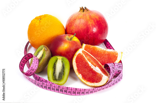 Diet concept: grapefruit orange pomegranate apple and measuring tape on white background