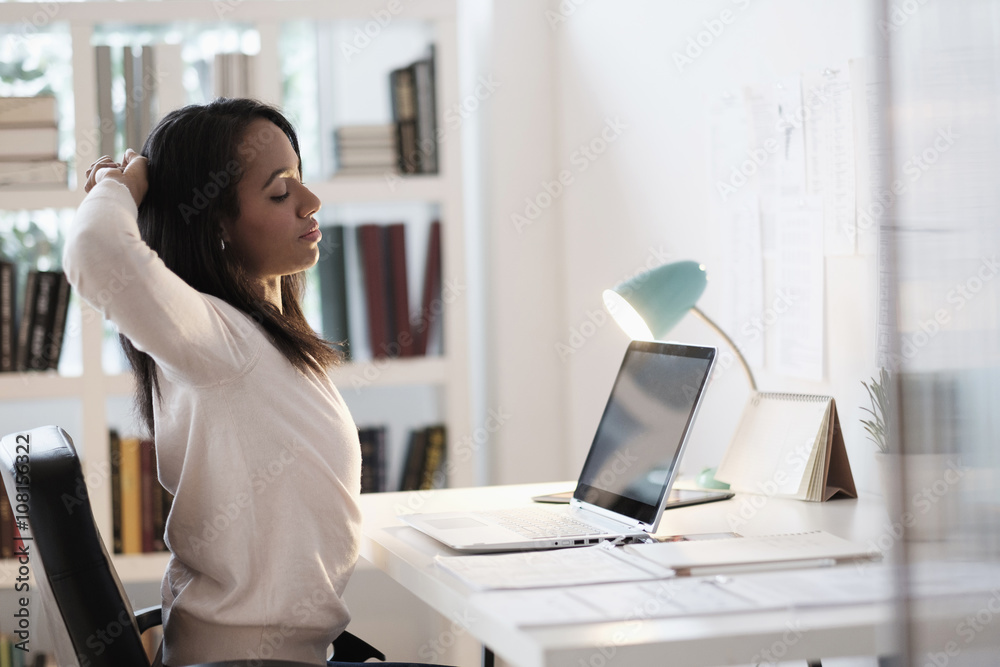 Mixed race businesswoman stretching at desk Mixed race businesswoman stretching at desk