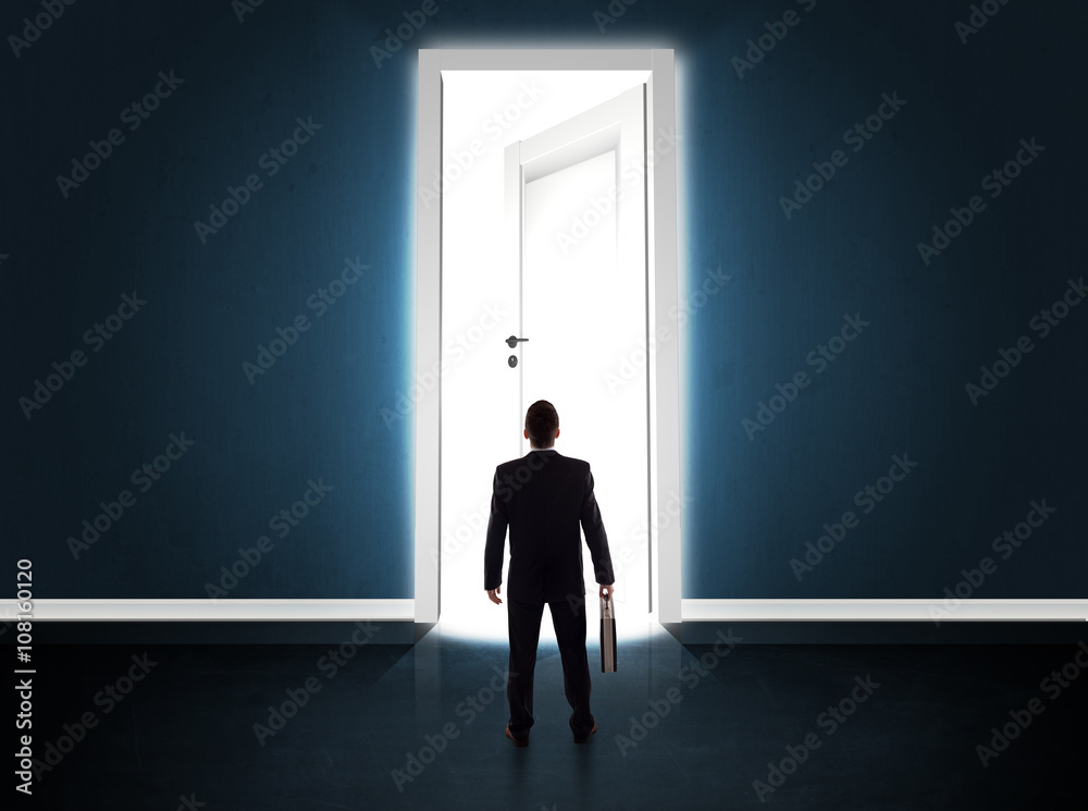 Business man looking at big bright opened door Business man looking at big bright opened door