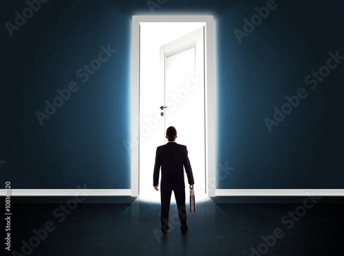 Business man looking at big bright opened door © ra2 studio