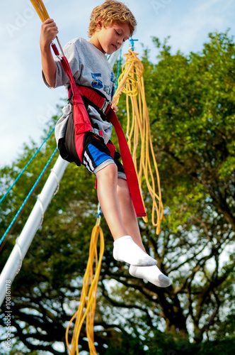 Little boy on a trampoline bungee jumping. photo