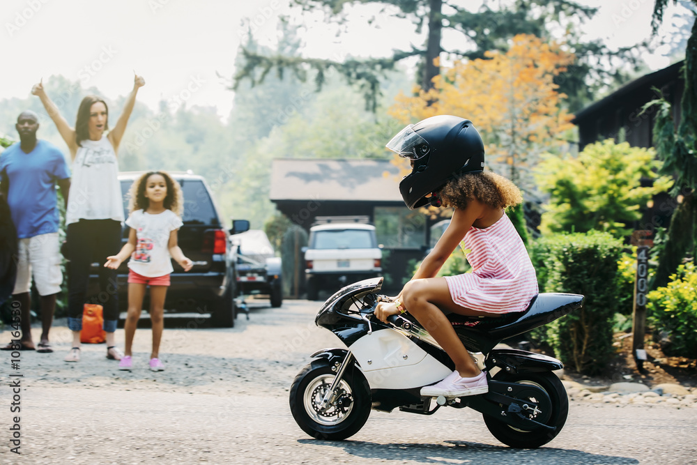 Girl riding miniature motorcycle on street Girl riding miniature motorcycle on street