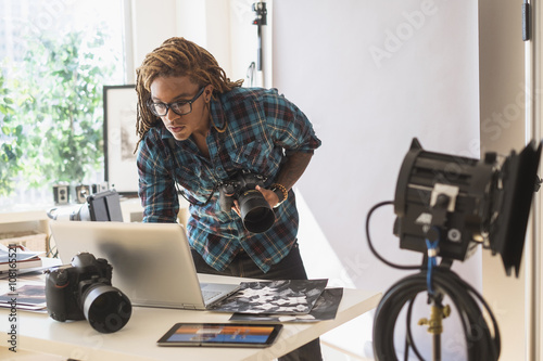 Mixed race photographer using laptop in studio photo