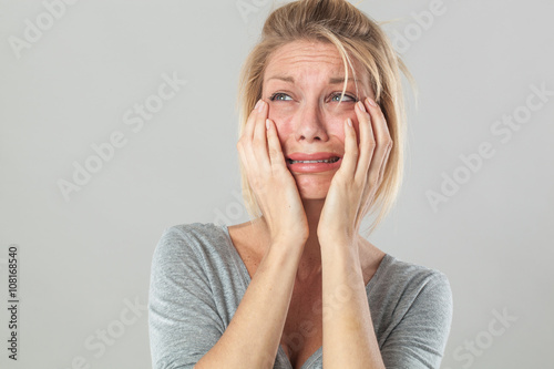 Fototapet drama concept - crying young blond woman in pain with big tears expressing her disappointment and sadness, grey background studio