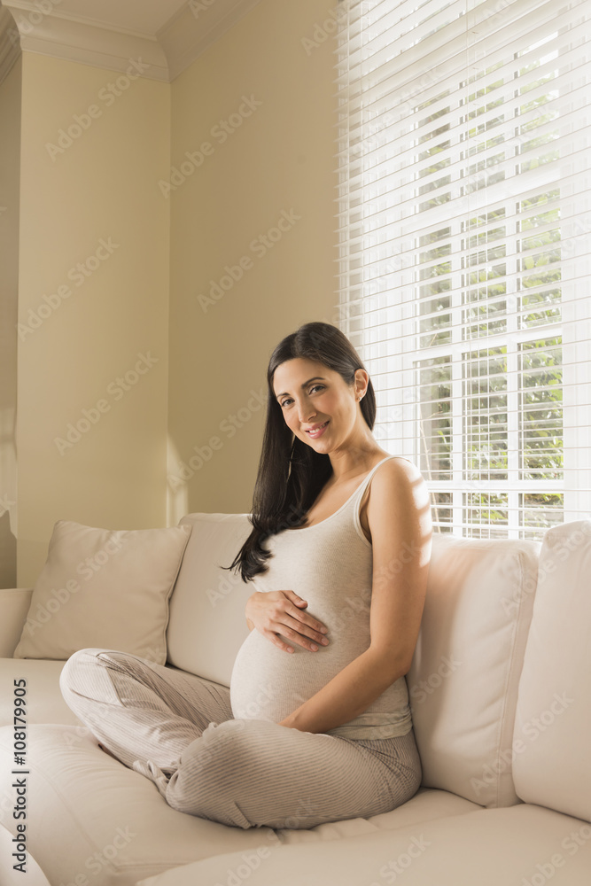 Pregnant Caucasian woman sitting on sofa Pregnant Caucasian woman sitting on sofa