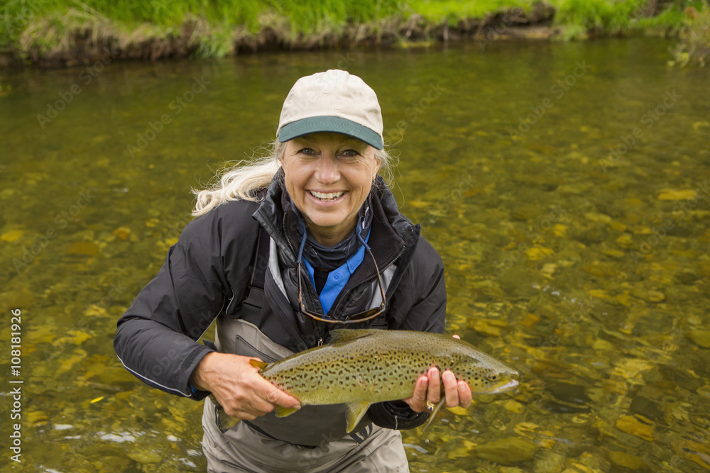 Caucasian woman holding fish in remote river Caucasian woman holding fish in remote river