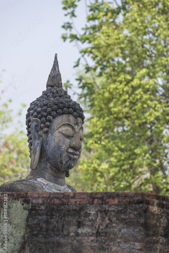 Obraz premium Big buddha image with green leafs background Sukhothai province Thailand.