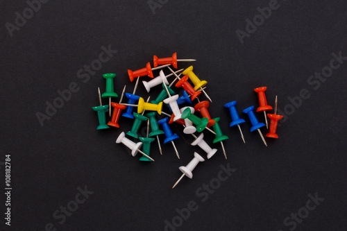 colored push pins on a black background