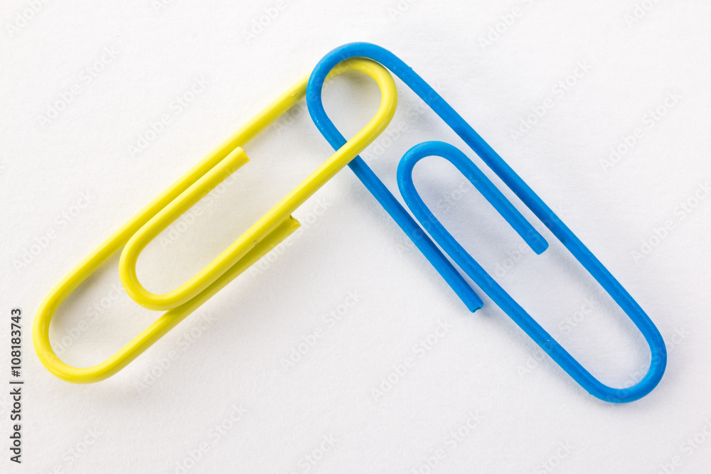 yellow and blue paper clips on a white background macro yellow and blue paper clips on a white background macro