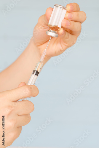 Nurse prepares to draw medication from glass vial
