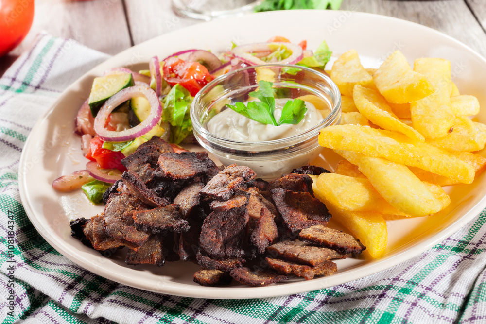 Grilled meat with French fries and fresh vegetables