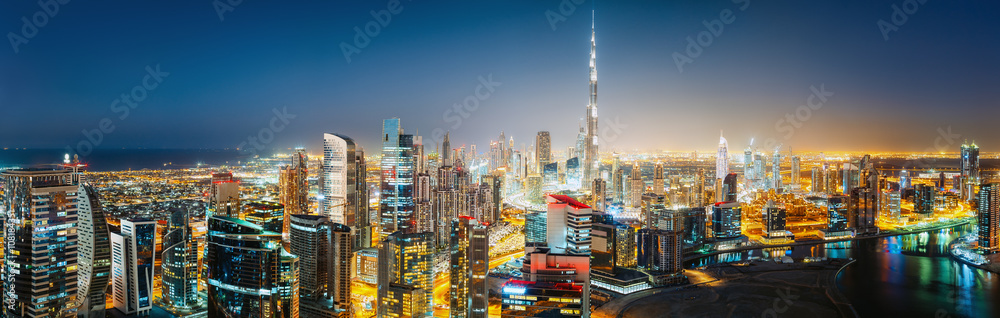 Fototapeta premium Panoramiczny widok z lotu ptaka na duże futurystyczne miasto nocą. Business Bay, Dubaj, Zjednoczone Emiraty Arabskie. Nocna panorama.
