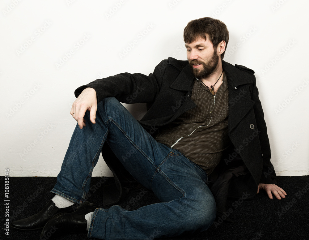 Handsome bearded elegant business man in a jacket, jeans and a woolen coat posing. feshion concept Handsome bearded elegant business man in a jacket, jeans and a woolen coat posing. feshion concept