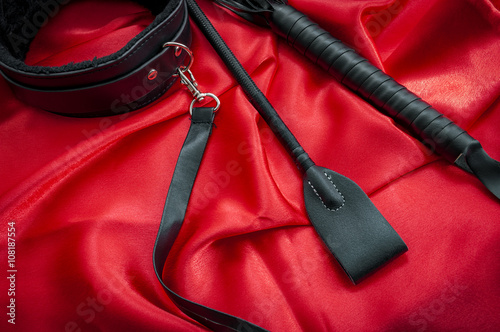 Принти на полотні Riding crop, a whip flogger, leather choker and leash on red satin, kinky sex to