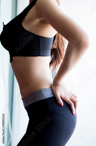 Shapely woman in a gym with a reflective afternoon by the window