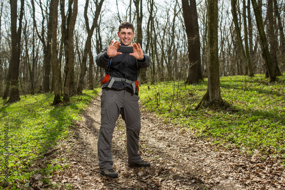 Man hiker taking photo with smart phone in forest Man hiker taking photo with smart phone in forest