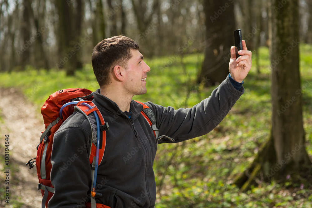 Fototapeta premium Man hiker taking photo with smart phone in forest