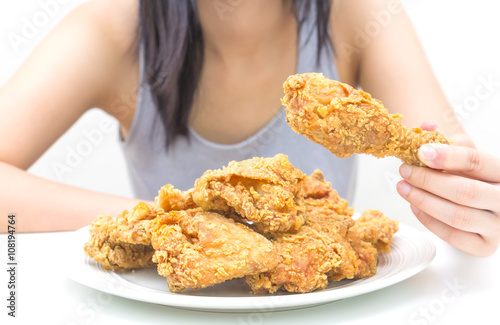 Woman holding and eatting fried chicken in white plate on white