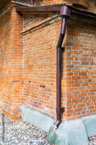 Fotografie drainpipe on red brick weathered wall