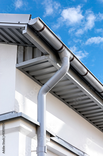 Foto new gray metal rain gutter on house rooftop
