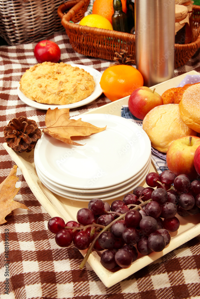 Composition of plates, fresh fruits and baking on checkered tablecloth