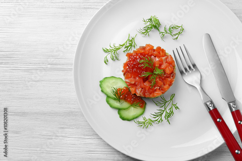 Delicious salmon tartare with red caviar on white plate