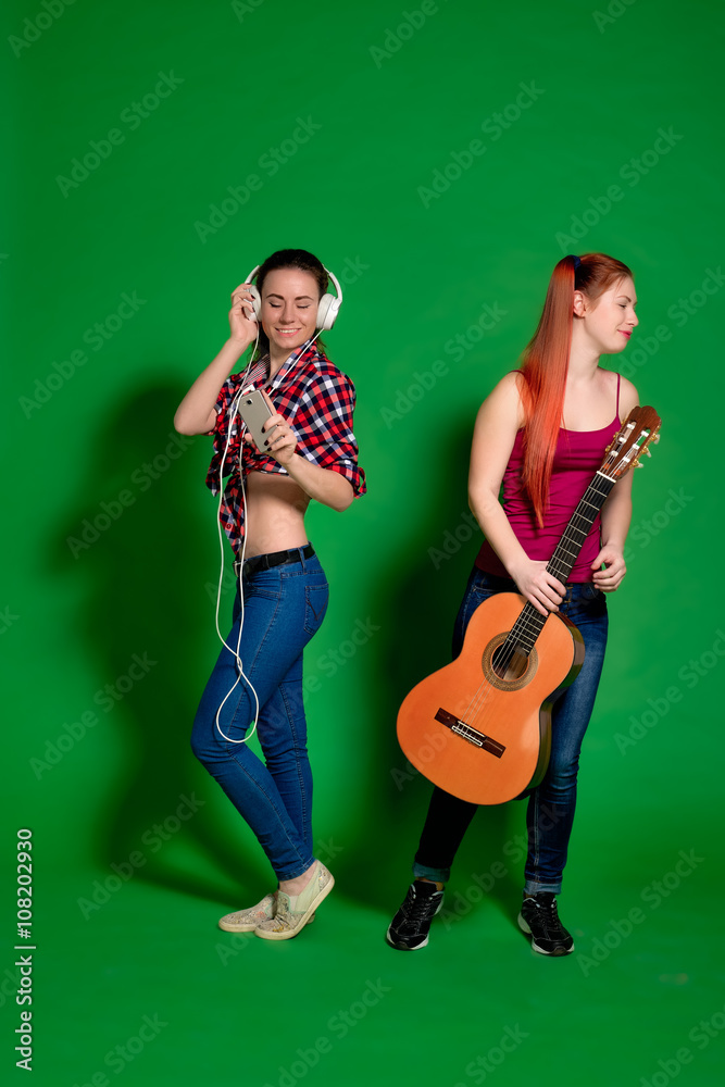 Two young women having fun, listening to music with headphones