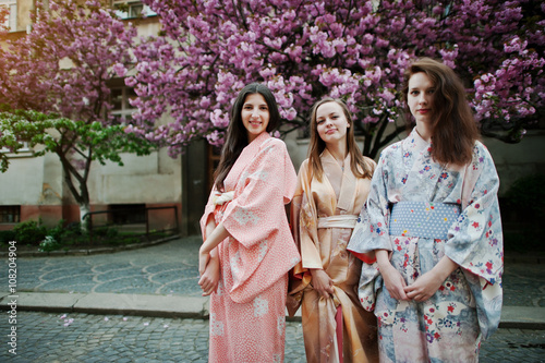 Three european girls wearing traditional japanese kimono backgro