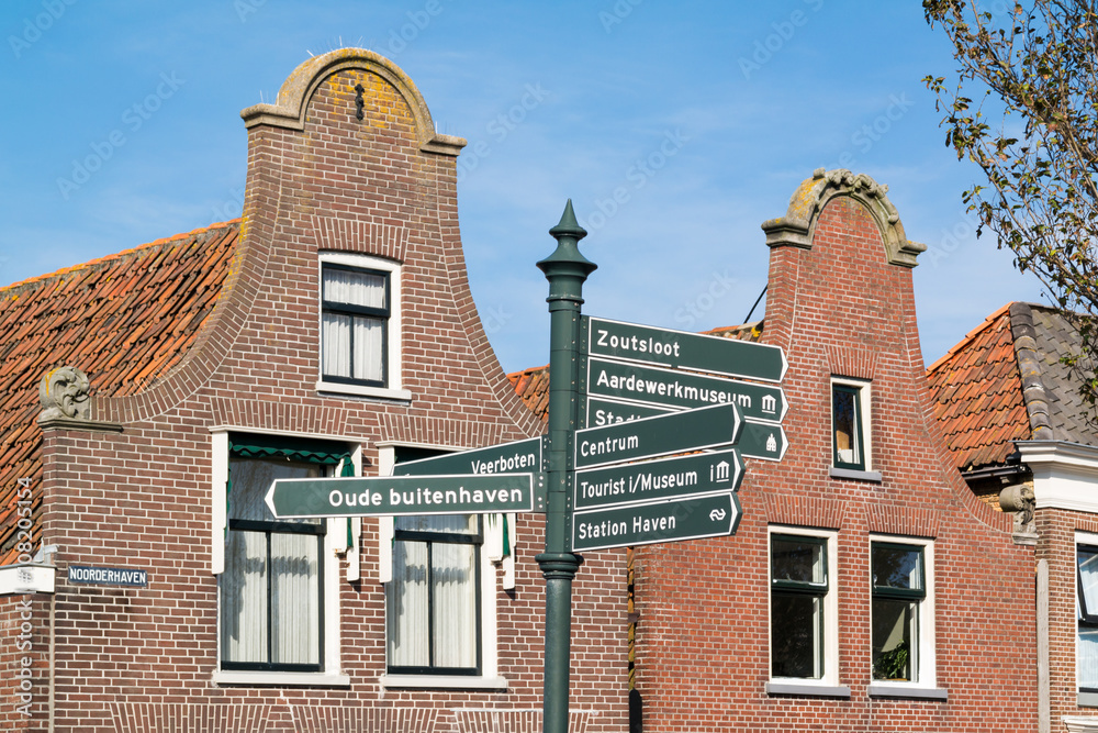 Clock gables of houses and sign post in historic old town of Harlingen, Friesland, Netherlands