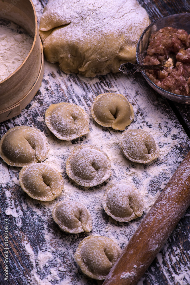 Fototapeta premium Raw meat dumplings. Ingredients for making dumplings: dough, minced meat, eggs on the wooden background