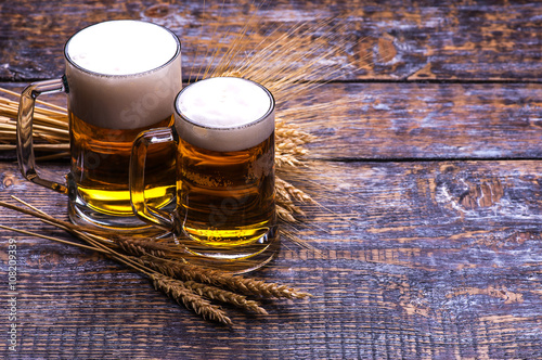 Beer light in a mug, ears of barley, wheat, isolated on wooden background