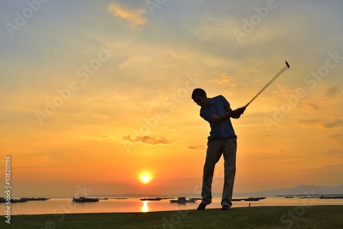 Young man playing golf at sunset